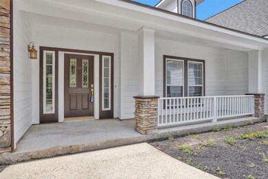 Covered front porch has conversation space and roo