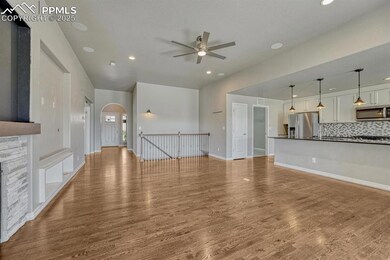 Step into the family room, where a ceiling fan, stone fireplace, and stunning wood floors converge to create a warm and inviting atmosphere, complete with a textured ceiling, walkout to the covered patio, and recessed lighting.