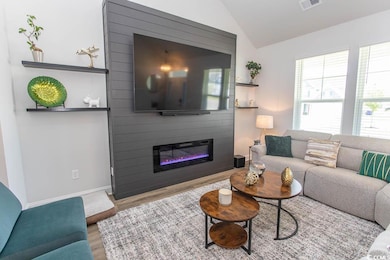 Living area featuring wood finished floors, a fireplace, and vaulted ceiling