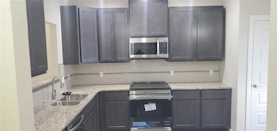 Kitchen with tasteful backsplash, stainless steel appliances, and light stone counters