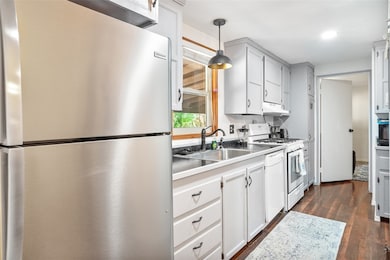 Kitchen with white appliances, a sink, dark wood-s