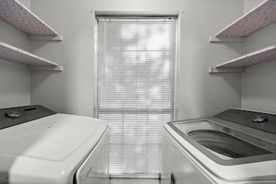 Laundry area with a textured wall and washer and clothes dryer