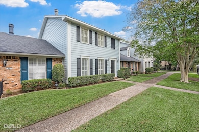 View of front of house with a shingled roof, a front lawn, and brick siding