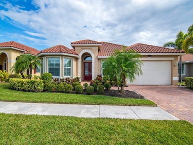Mediterranean / spanish-style house with stucco siding, decorative driveway, a front yard, a garage, and a tile roof