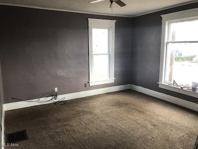 Carpeted empty room featuring ornamental molding and ceiling fan