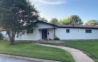 Ranch-style house with a front lawn, brick siding, and covered porch