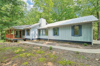 View of front of house featuring a porch, a chimney, and metal roof