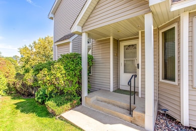 Covered side entryway with columns, an accessible railing, and framed by lush landscaping..