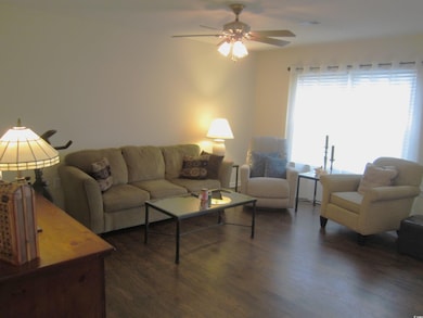 Living room featuring ceiling fan and dark wood-ty