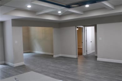 Spare room featuring coffered ceiling, wood finished floors, baseboards, recessed lighting, and beam ceiling