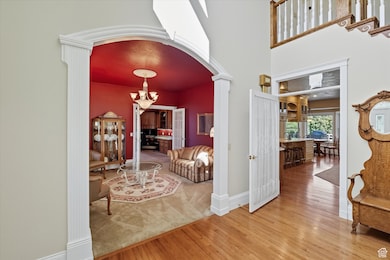 Entryway with arched walkways, hardwood / wood-style floors, a chandelier, and a towering ceiling