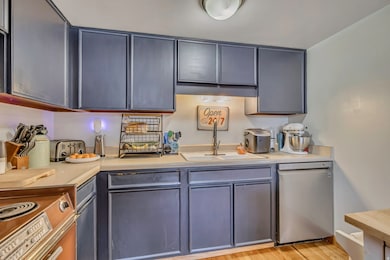 Kitchen with light countertops, dishwasher, gray cabinets, light wood finished floors, and range with electric cooktop