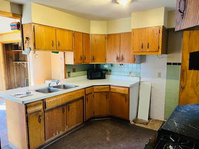 Kitchen featuring brown cabinetry, light countertops, decorative backsplash, and black appliances