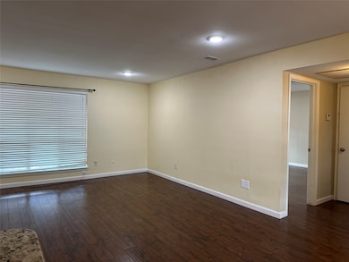 Empty room featuring dark wood-style floors and baseboards
