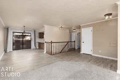 Spare room with a textured ceiling, crown molding, a chandelier, light wood-style flooring, and light carpet