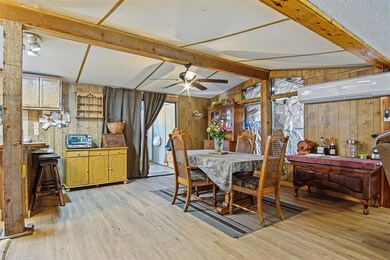 Dining space with wooden walls, light wood-style floors, a wall unit AC, a ceiling fan, and healthy amount of natural light