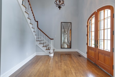 Entryway featuring wood finished floors, french doors, stairway, and a high ceiling