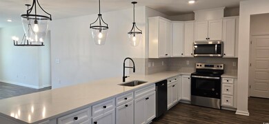 Kitchen with stainless steel appliances, a sink, dark wood-style flooring, a peninsula, and tasteful backsplash
