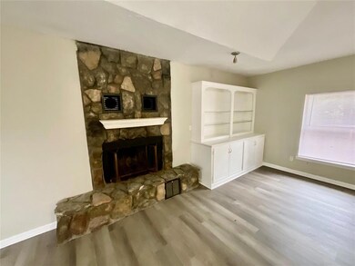 Living room with a stone fireplace and wood-type f