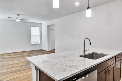 Kitchen featuring a sink, visible vents, dishwasher, an island with sink, and decorative light fixtures