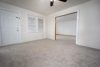 Carpeted empty room featuring baseboards and a ceiling fan