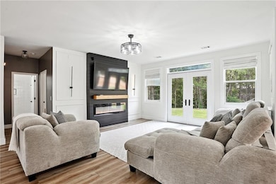 Living area with a large fireplace, light wood finished floors, baseboards, and french doors