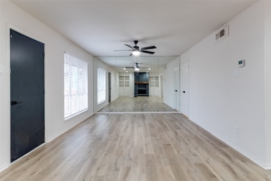 Unfurnished living room featuring a fireplace, light wood finished floors, a ceiling fan, and built in shelves