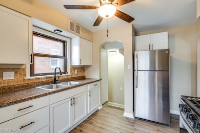 Kitchen with white cabinetry, sink, appliances with stainless steel finishes, and backsplash