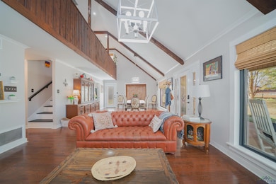 Living room with beam ceiling, stairway, dark wood-type flooring, high vaulted ceiling, and healthy amount of natural light