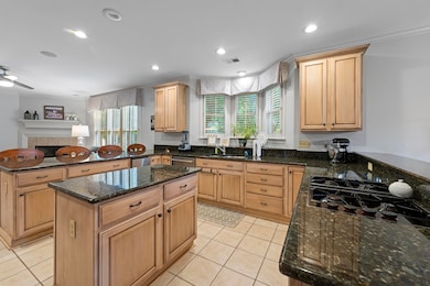 Culinary enthusiasts will delight in the gourmet eat-in kitchen, equipped with granite countertops, a central island, breakfast bar, built-in desk area, gas range, stainless steel appliances, double oven, and a trash compactor.