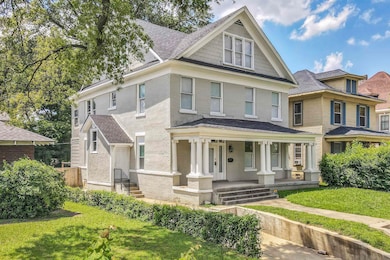 View of front facade featuring brick siding, roof with shingles, covered porch, and a front yard