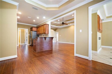 Kitchen with freestanding refrigerator, a tray ceiling, a ceiling fan, crown molding, and a breakfast bar