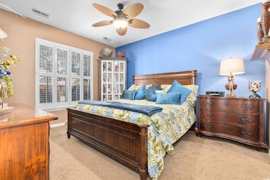 Carpeted bedroom featuring a ceiling fan
