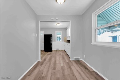 Hall with light wood-type flooring, visible vents, and baseboards