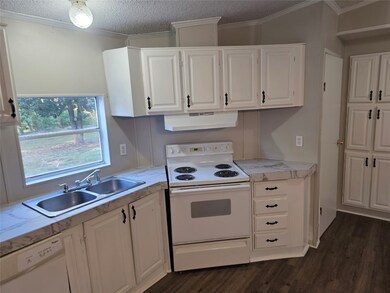 Kitchen featuring white appliances, dark wood finished floors, light countertops, ornamental molding, and white cabinets