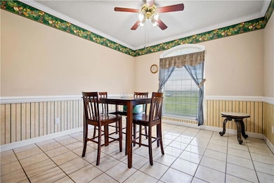 Dining room featuring a wainscoted wall, a textured ceiling, ornamental molding, wooden walls, and light tile patterned floors