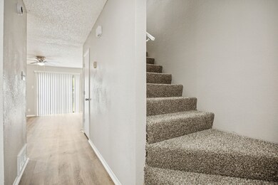Stairs featuring wood finished floors, a textured wall, a textured ceiling, and ceiling fan