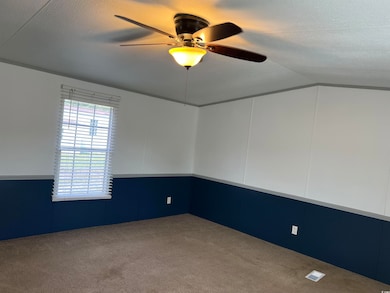 Carpeted empty room with lofted ceiling and ceiling fan