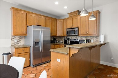 Kitchen with backsplash, a kitchen breakfast bar, decorative light fixtures, kitchen peninsula, and stainless steel appliances