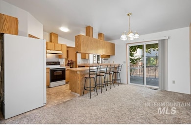 Kitchen with white appliances, vaulted ceiling, a chandelier, a peninsula, and a breakfast bar area