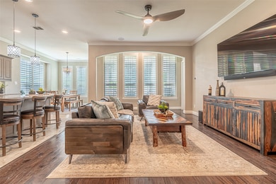 Living room featuring crown molding, dark wood-type flooring, a ceiling fan, and recessed lighting
