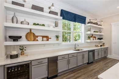 Kitchen with open shelves, gray cabinetry, beverage cooler, dark wood-type flooring, and crown molding