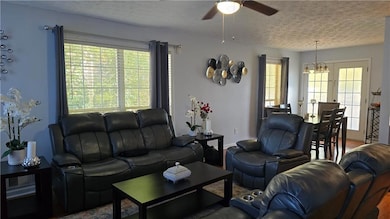 Living area with wood finished floors, a textured ceiling, a chandelier, and a ceiling fan