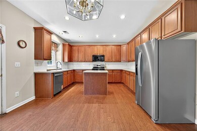Kitchen with appliances with stainless steel finishes, brown cabinetry, light wood-style floors, recessed lighting, and a center island