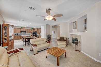 Living area featuring arched walkways, a ceiling fan, light tile patterned floors, a tiled fireplace, and recessed lighting