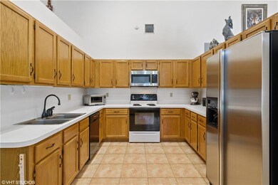 Kitchen with wood cabinets, double sink and s/s refrigerator and microwave.
