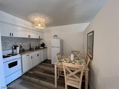 Kitchen with white cabinets, white appliances, dar