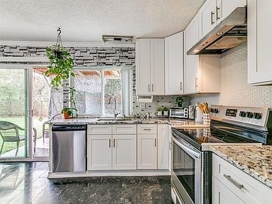 Kitchen with stainless steel appliances, plenty of natural light, under cabinet range hood, backsplash, and a textured ceiling