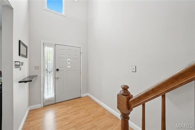 Foyer entrance with plenty of natural light, light wood-style floors, stairway, and a towering ceiling