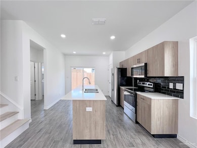 Kitchen featuring stainless steel appliances, a sink, a center island with sink, modern cabinets, and recessed lighting